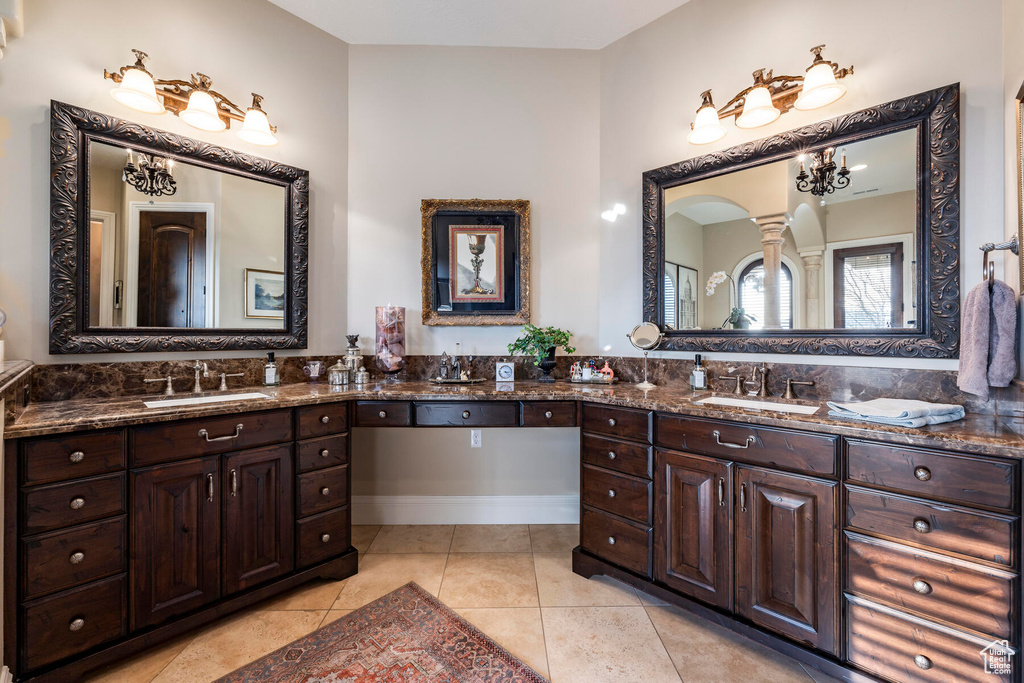 Bathroom featuring dual sinks, tile floors, large vanity, and a notable chandelier