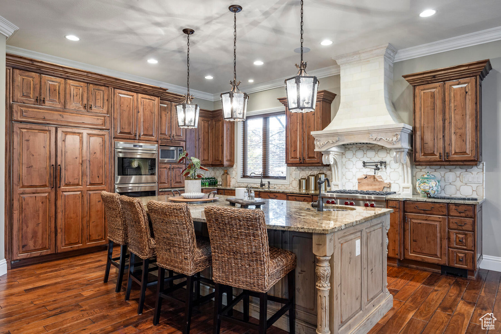 Kitchen with a kitchen island with sink, a breakfast bar, custom exhaust hood, and dark hardwood / wood-style floors