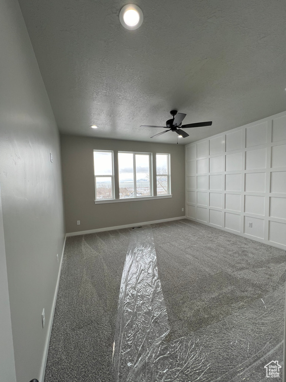 Spare room featuring carpet, a textured ceiling, and ceiling fan