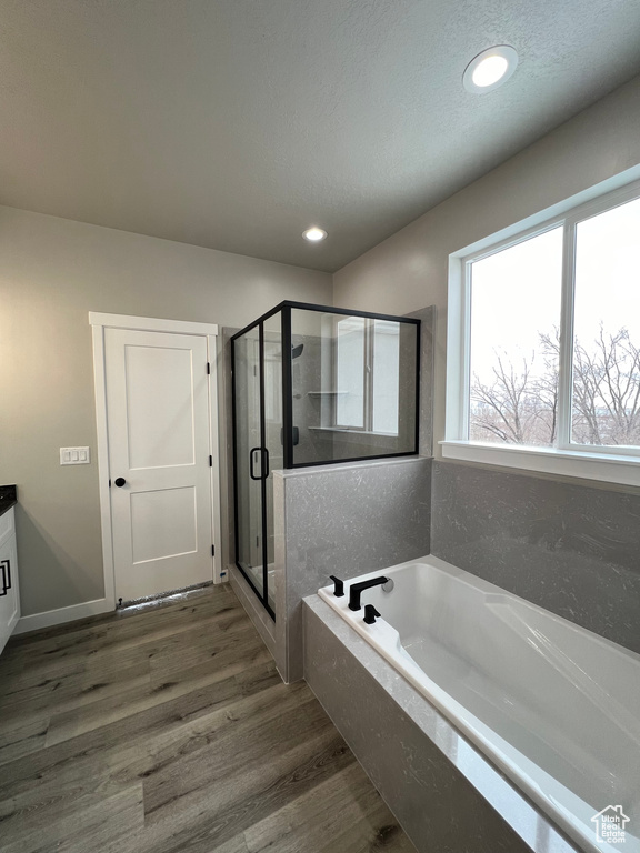Bathroom with vanity, separate shower and tub, a textured ceiling, and hardwood / wood-style flooring
