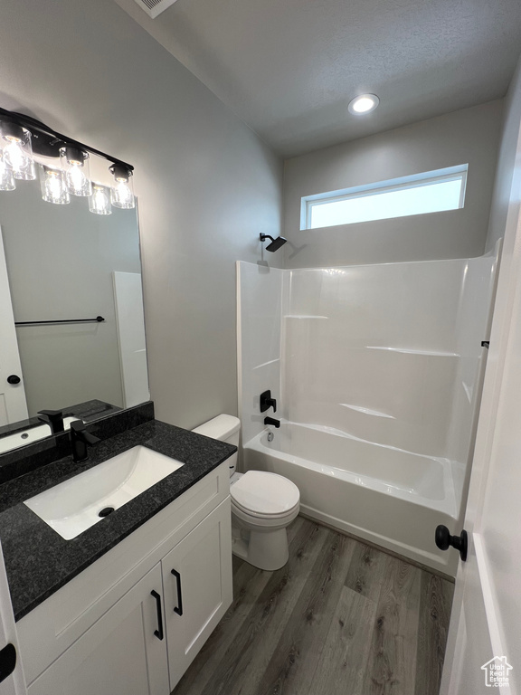 Full bathroom featuring wood-type flooring, toilet, washtub / shower combination, and oversized vanity