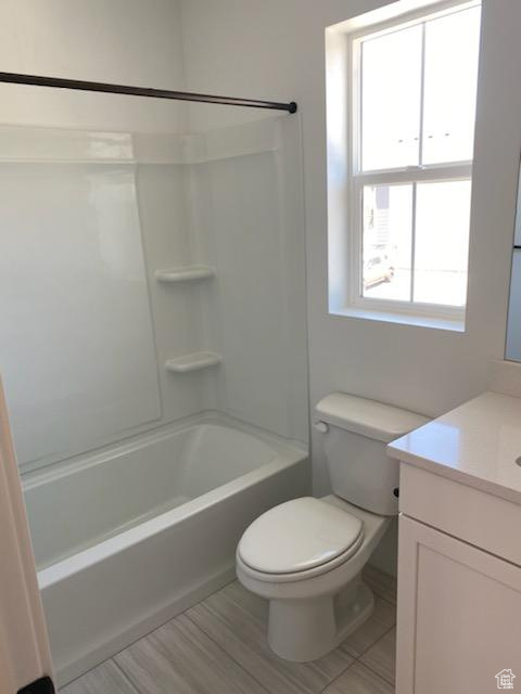 Full bathroom featuring tile floors, toilet, vanity, and washtub / shower combination