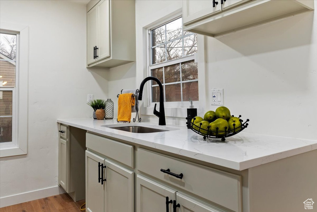 Bar featuring light hardwood / wood-style floors, light stone counters, and sink