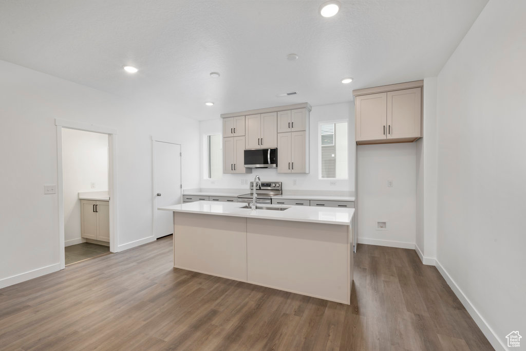 Kitchen featuring appliances with stainless steel finishes, an island with sink, and hardwood / wood-style flooring