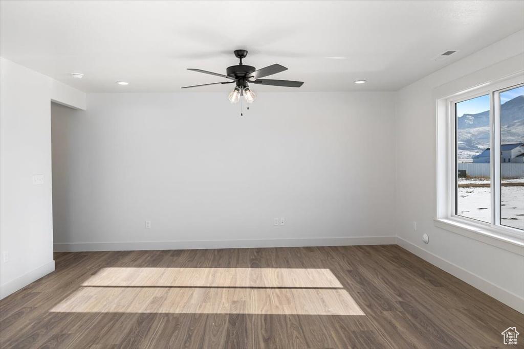 Spare room featuring dark hardwood / wood-style flooring, a wealth of natural light, and ceiling fan