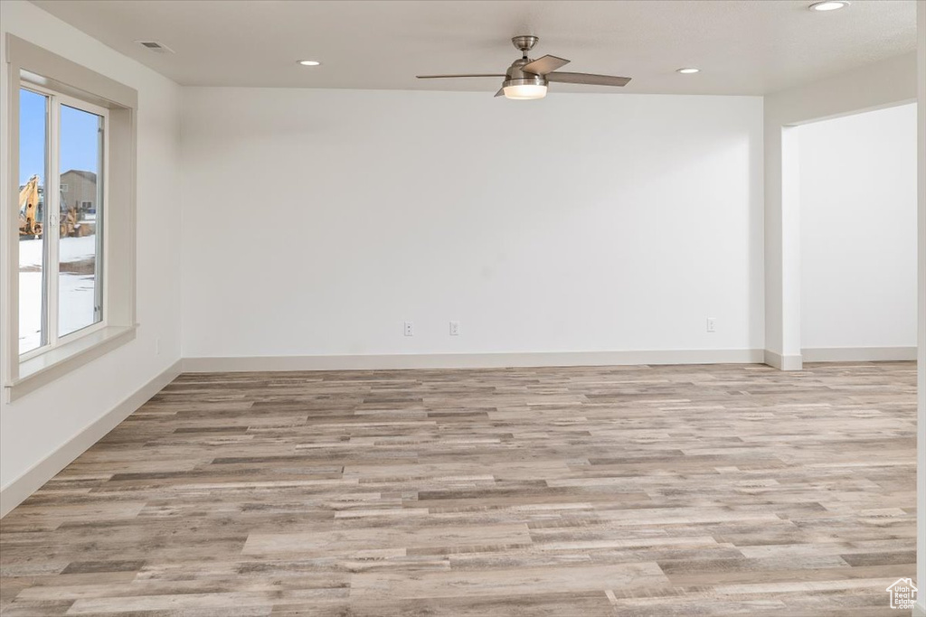 Empty room with light hardwood / wood-style flooring, a healthy amount of sunlight, and ceiling fan