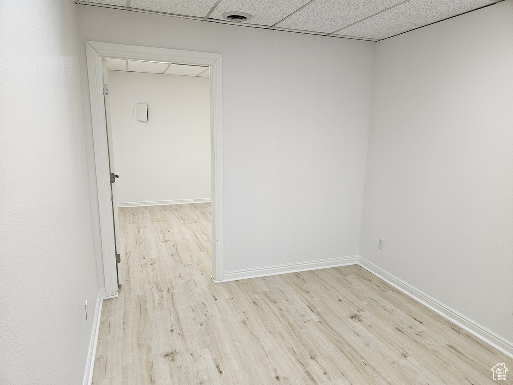 Unfurnished room with light hardwood / wood-style floors and a drop ceiling