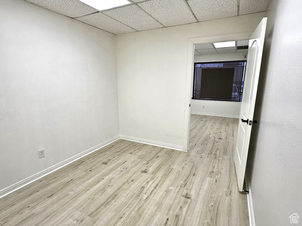 Unfurnished room with light hardwood / wood-style floors and a paneled ceiling