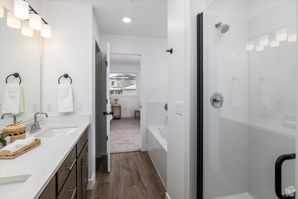 Bathroom with double vanity, plus walk in shower, and hardwood / wood-style floors