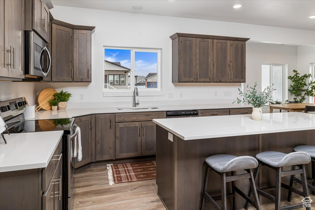 Kitchen with sink, plenty of natural light, appliances with stainless steel finishes, and light hardwood / wood-style flooring