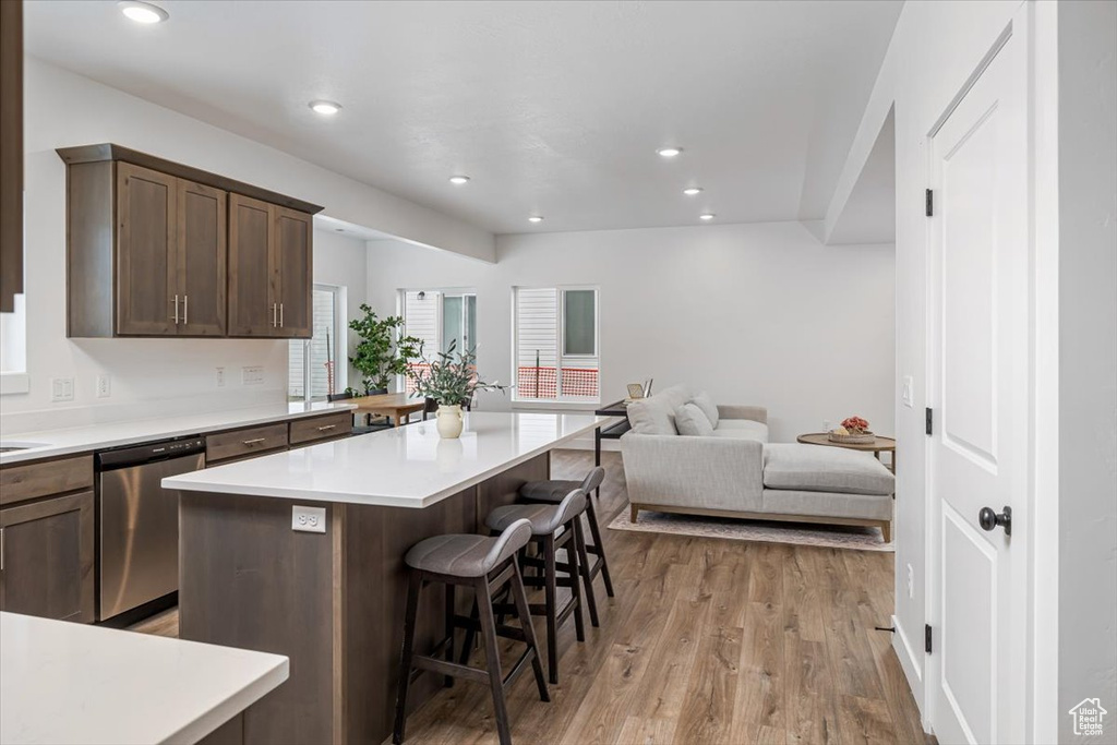 Kitchen with a kitchen bar, dishwasher, a center island, light hardwood / wood-style flooring, and dark brown cabinets