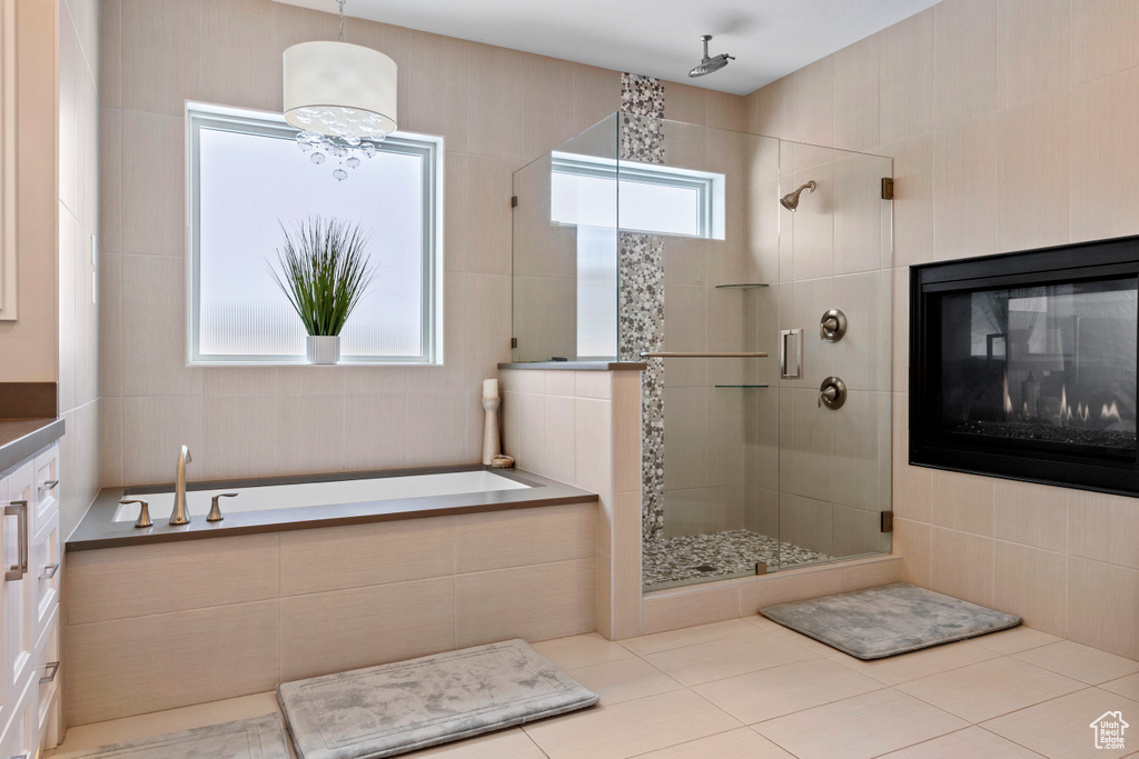 Bathroom with vanity, a tile fireplace, a notable chandelier, separate shower and tub, and tile flooring