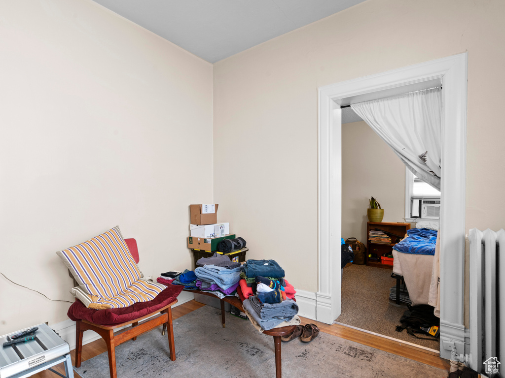 Living area with hardwood / wood-style floors and radiator heating unit