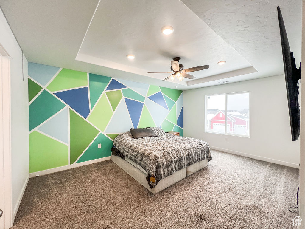 Bedroom with a raised ceiling, a textured ceiling, carpet, and ceiling fan