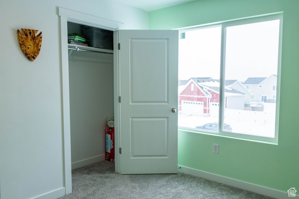 Unfurnished bedroom with a closet, multiple windows, and light colored carpet