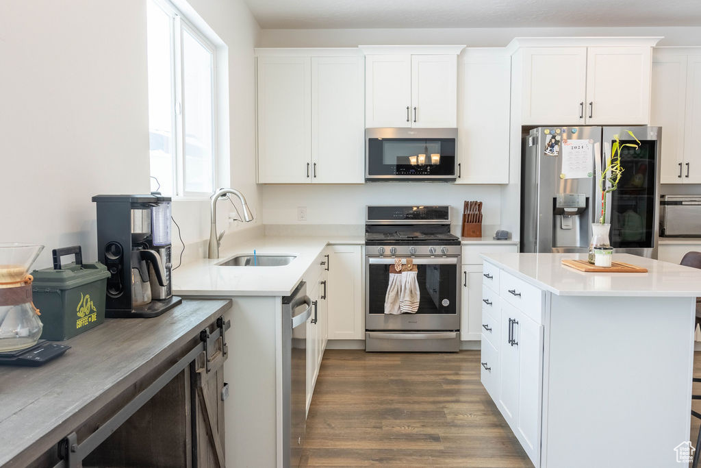 Kitchen featuring hardwood / wood-style floors, white cabinets, sink, and appliances with stainless steel finishes