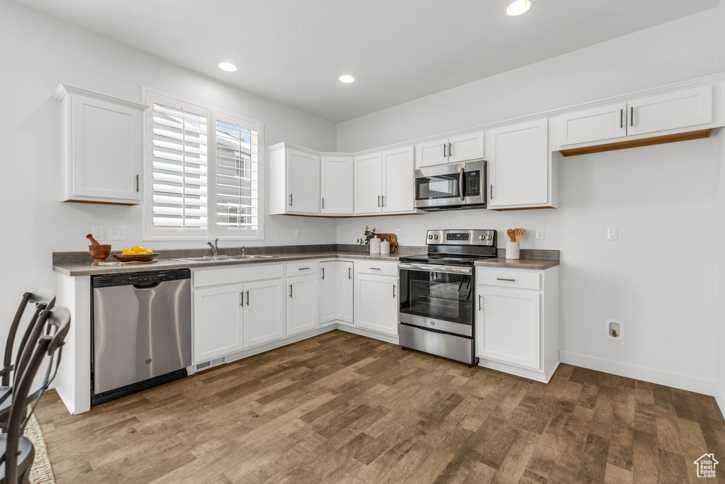 Kitchen featuring dark hardwood / wood-style floors, white cabinetry, sink, and appliances with stainless steel finishes