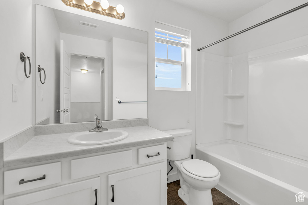 Full bathroom featuring wood-type flooring, toilet, large vanity, and shower / bathtub combination