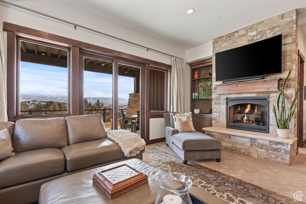 Carpeted living room with a stone fireplace, built in shelves, and a mountain view