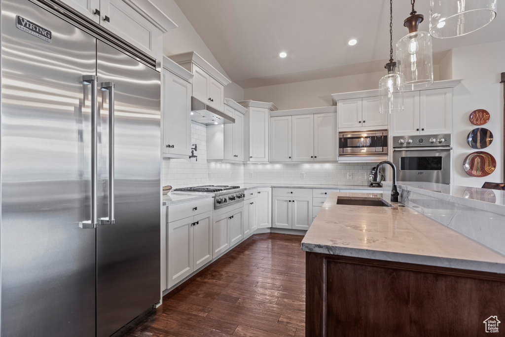 Kitchen featuring built in appliances, sink, tasteful backsplash, dark hardwood / wood-style floors, and white cabinetry