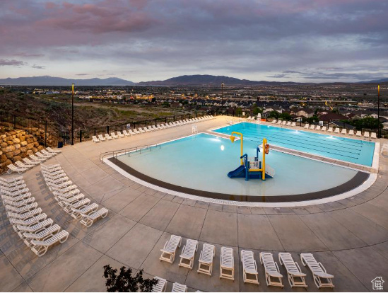 Pool at dusk with a patio and a mountain view