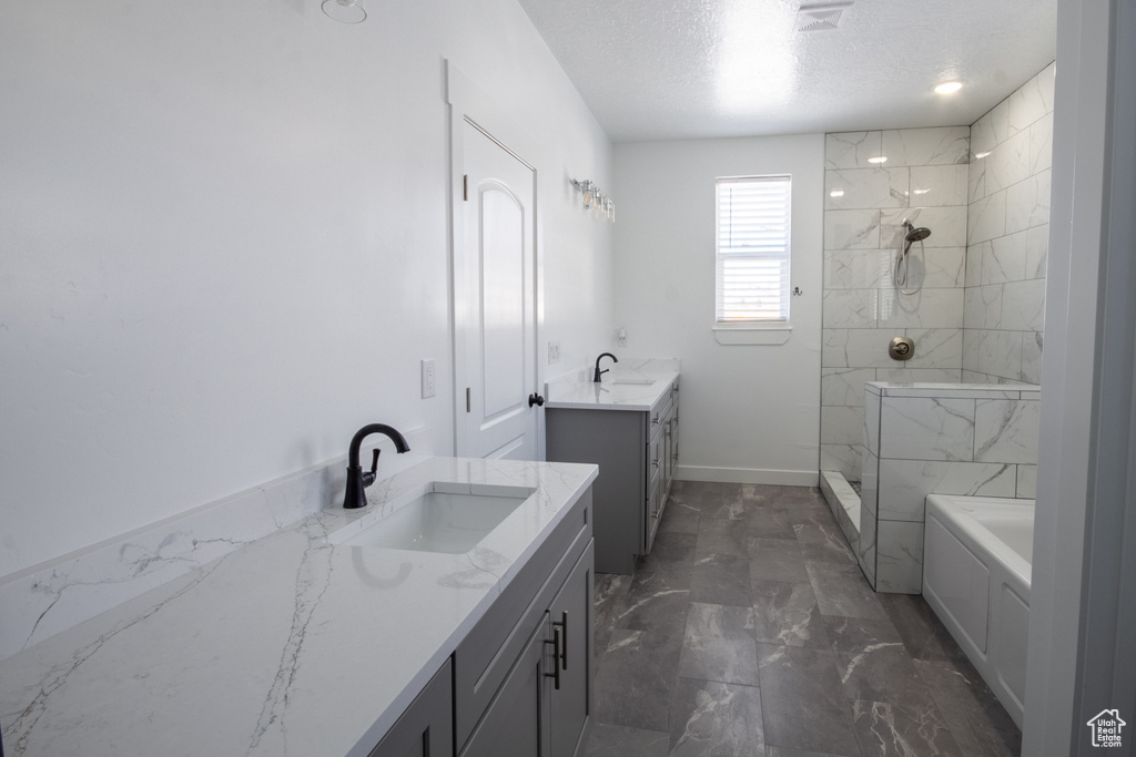 Bathroom featuring tile floors, double sink vanity, plus walk in shower, and a textured ceiling