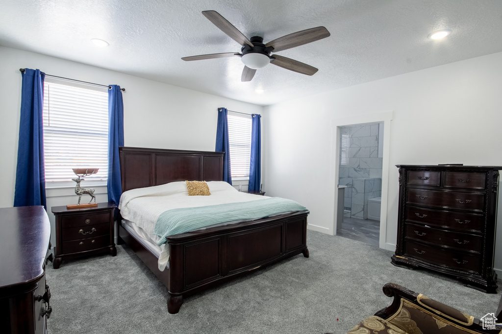 Carpeted bedroom with ensuite bath, a textured ceiling, and ceiling fan