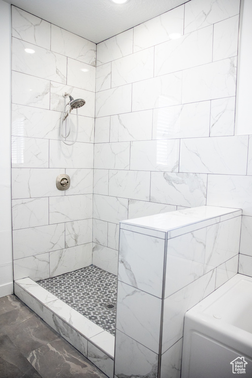 Bathroom featuring tile walls, a tile shower, and tile floors