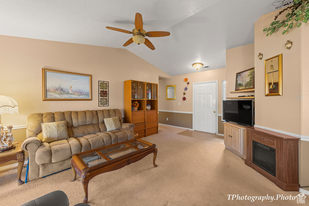 Carpeted living room with lofted ceiling and ceiling fan