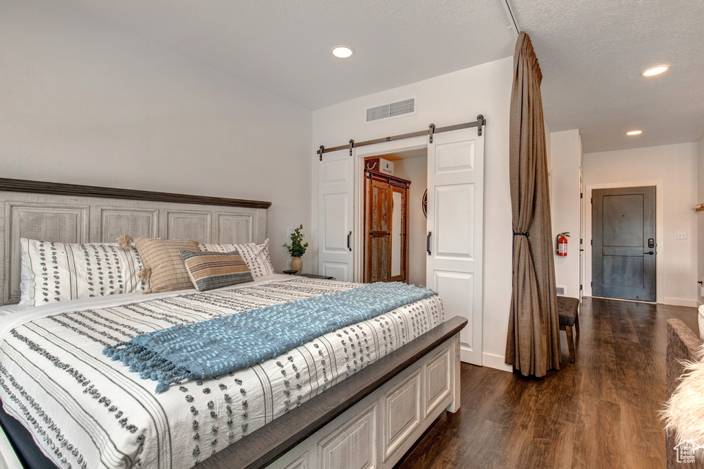 Bedroom with a barn door and dark hardwood / wood-style floors