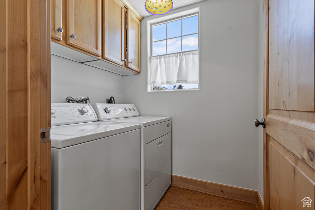 Laundry room with independent washer and dryer, cabinets, and hardwood / wood-style floors