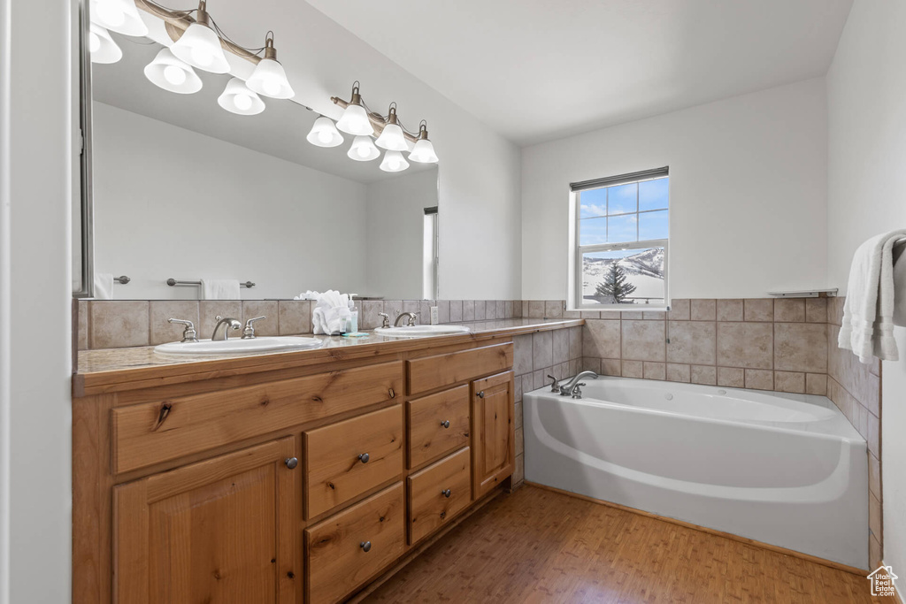 Bathroom with wood-type flooring, a washtub, and dual vanity