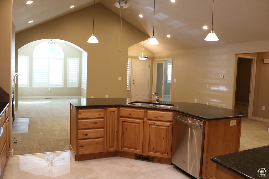 Kitchen featuring dark stone countertops, hanging light fixtures, light tile floors, stainless steel dishwasher, and sink