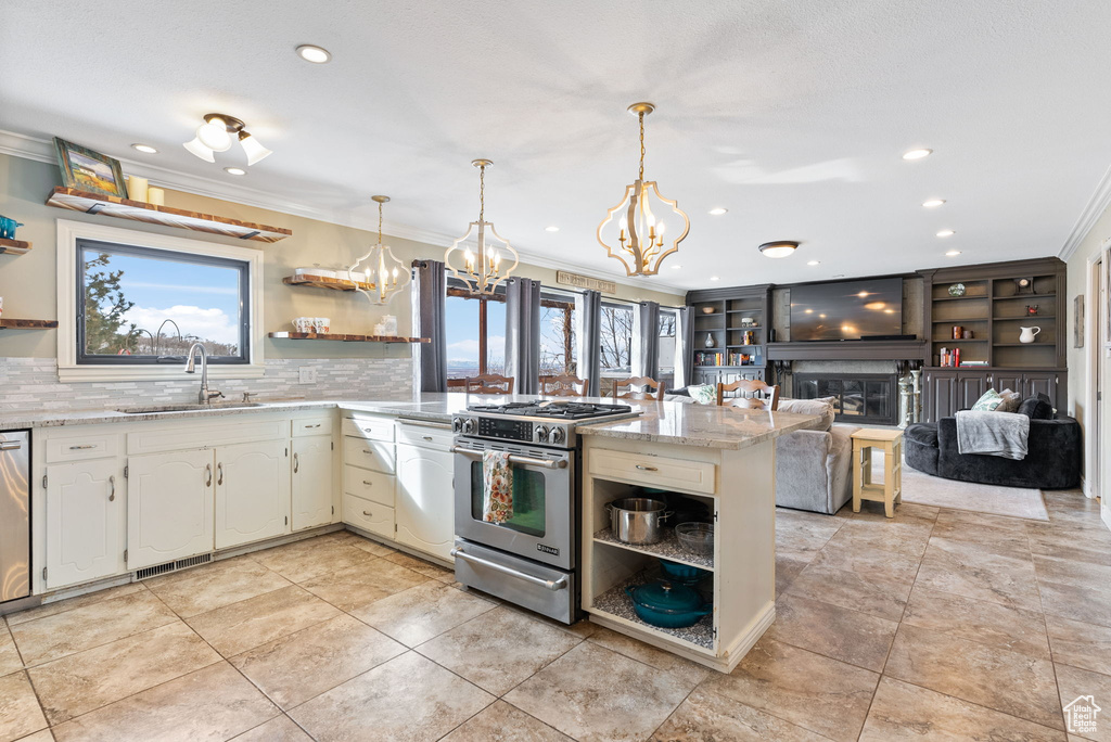 Kitchen featuring a chandelier, a large fireplace, stainless steel appliances, sink, and tasteful backsplash