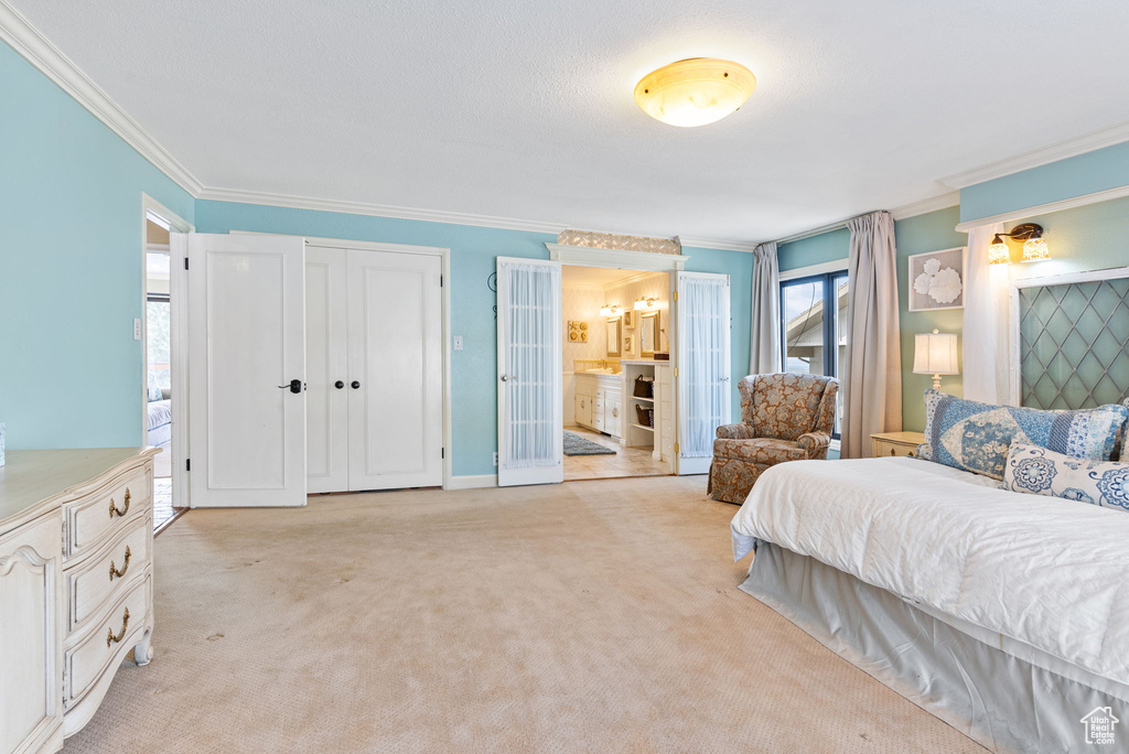 Bedroom featuring crown molding, light colored carpet, and ensuite bath