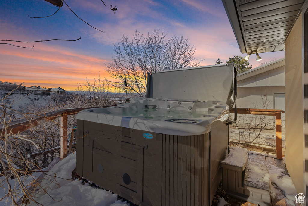 Snow covered patio featuring a hot tub