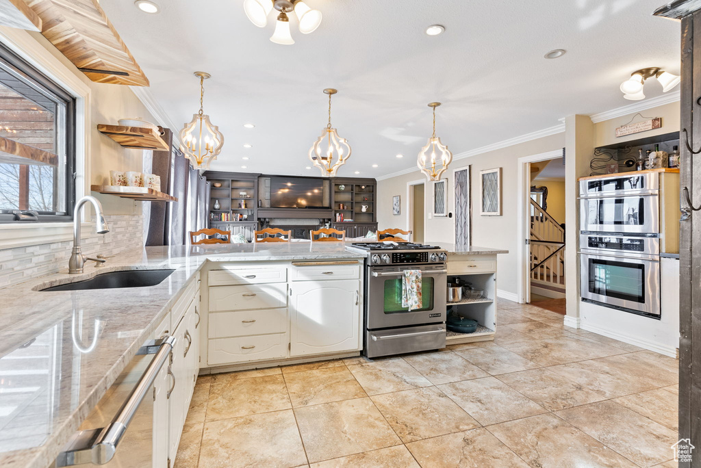 Kitchen with pendant lighting, appliances with stainless steel finishes, backsplash, white cabinets, and sink