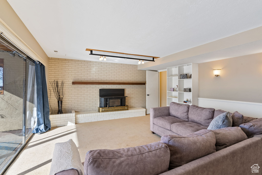 Carpeted living room featuring a fireplace, brick wall, and track lighting