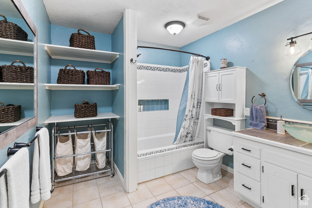 Full bathroom with vanity, a textured ceiling, tile floors, toilet, and shower / bath combo