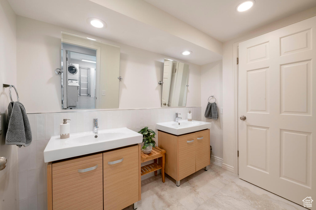 Bathroom with tile walls, dual vanity, tile flooring, and backsplash