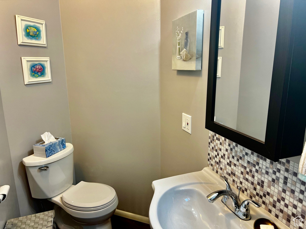 Bathroom featuring sink, tasteful backsplash, and toilet