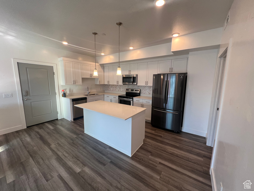 Kitchen with dark hardwood / wood-style flooring, white cabinets, a center island, stainless steel appliances, and sink