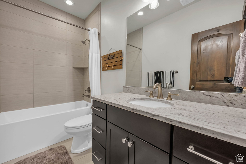 Full bathroom with shower / bath combo with shower curtain, toilet, tile floors, and vanity with extensive cabinet space