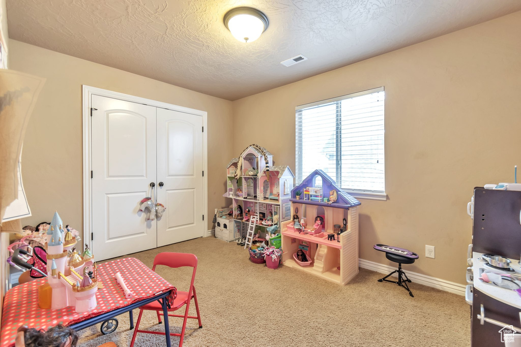Playroom featuring light colored carpet and a textured ceiling