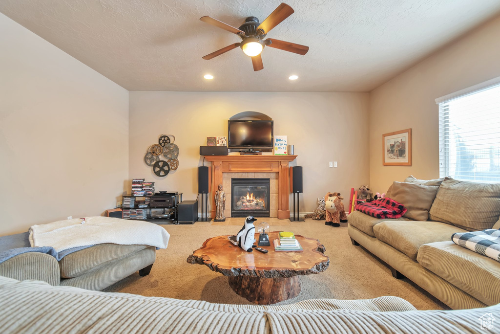 Carpeted living room with a fireplace and ceiling fan