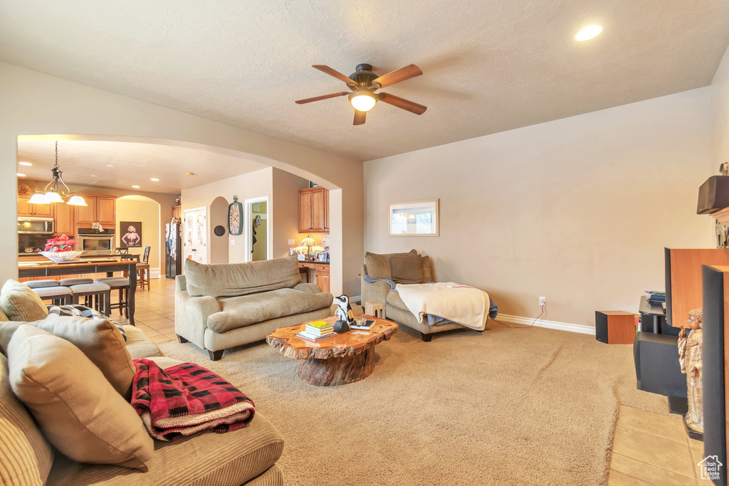 Living room with light carpet, a textured ceiling, and ceiling fan