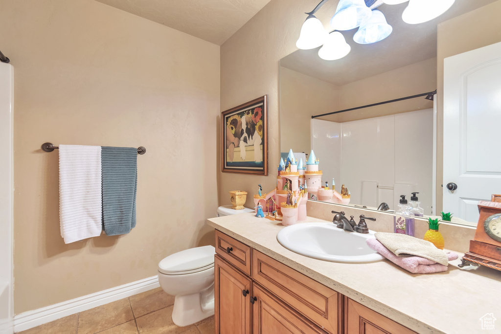 Bathroom with large vanity, toilet, tile flooring, and a notable chandelier