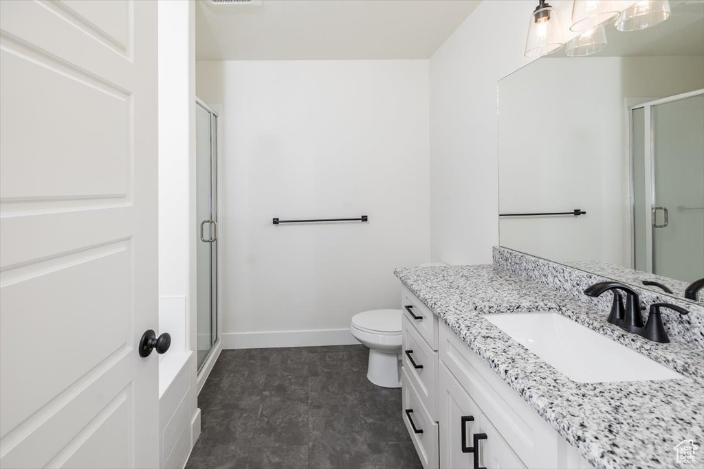 Bathroom featuring tile floors, walk in shower, toilet, and large vanity