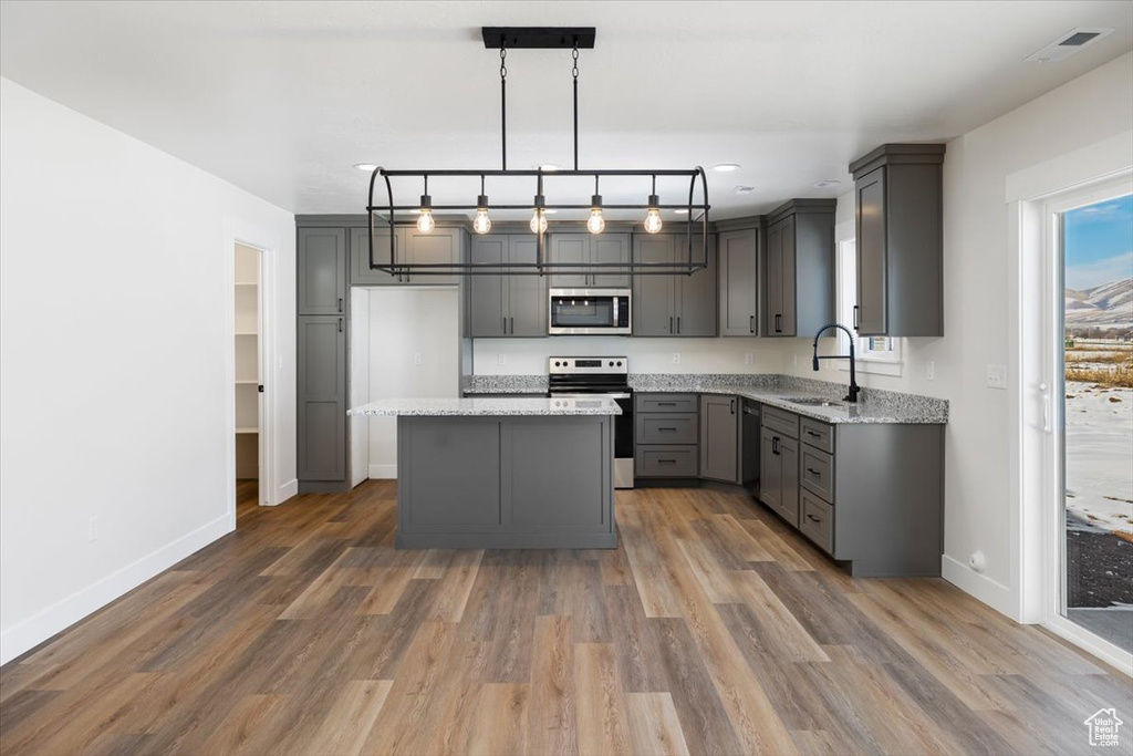 Kitchen featuring gray cabinets, hanging light fixtures, appliances with stainless steel finishes, sink, and a center island