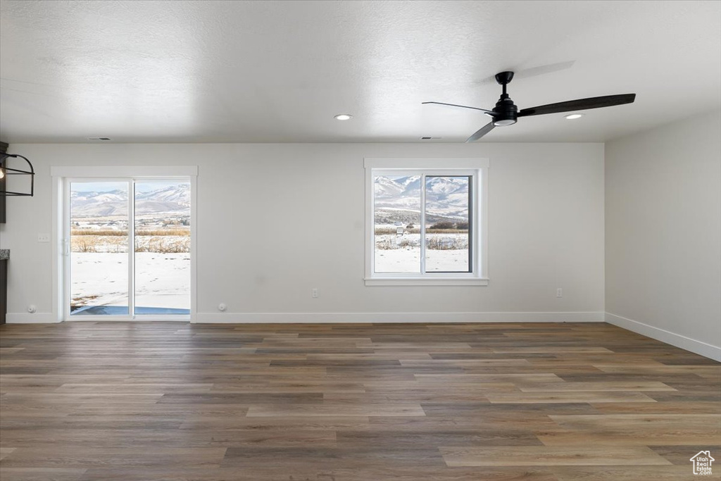 Empty room featuring dark wood-type flooring, a wealth of natural light, and ceiling fan